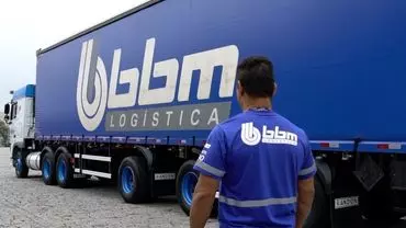 A foto mostra uma carreta 3 eixos da BBM Logística e um motorista da empresa