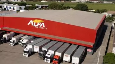 A foto mostra vários caminhões e carretas da empresa Alfa Transportes