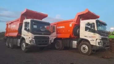 A foto mostra dois caminhões 6x4 basculantes da empresa Tradimaq