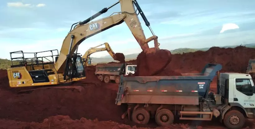 A foto mostra uma escavadeira e um caminhão da Construtora Vale Verde